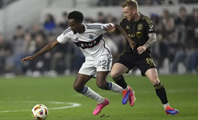 Vancouver Whitecaps forward Ali Ahmed (22) controls the ball against Los Angeles FC midfielder Lewis O'Brien (8) during the first half of the first soccer match of an MLS Cup playoffs opening round in Los Angeles, Sunday, Oct. 27, 2024. (AP Photo/Alex Gallardo)