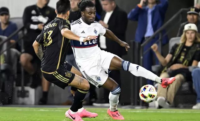 Vancouver Whitecaps defender Sam Adekugbe, right, controls the ball against Los Angeles FC forward Cristian Olivera (13) during the first half of the first match of an MLS Cup playoffs opening round in Los Angeles, Sunday, Oct. 27, 2024. (AP Photo/Alex Gallardo)