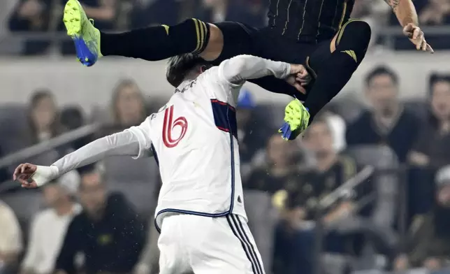 Los Angeles FC forward Olivier Giroud, top, leaps over Vancouver Whitecaps defender Tristan Blackmon (6) during the first half of the first soccer match of an MLS Cup playoffs opening round in Los Angeles, Sunday, Oct. 27, 2024. (AP Photo/Alex Gallardo)