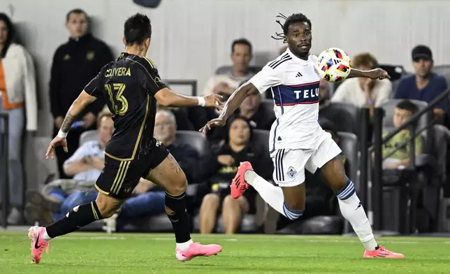 Vancouver Whitecaps defender Sam Adekugbe, right, controls the ball against Los Angeles FC forward Cristian Olivera (13) during the first half of the first soccer match of an MLS Cup playoffs opening round in Los Angeles, Sunday, Oct. 27, 2024. (AP Photo/Alex Gallardo)