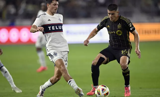 Vancouver Whitecaps midfielder Alessandro Schöpf, left, kicks the ball past Los Angeles FC defender Sergi Palencia (14) during the second half of the first match of an MLS Cup playoffs opening round in Los Angeles, Sunday, Oct. 27, 2024. (AP Photo/Alex Gallardo)