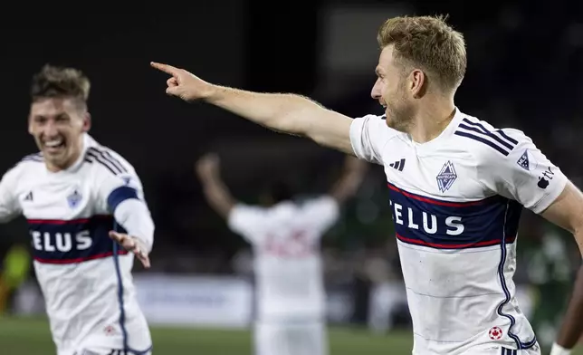 Vancouver Whitecaps midfielder Stuart Armstrong, right, celebrates the goal against the Portland Timbers during the second half of an MLS soccer match Wednesday, Oct. 23, 2024, in Portland, Ore. (AP Photo/Howard Lao)