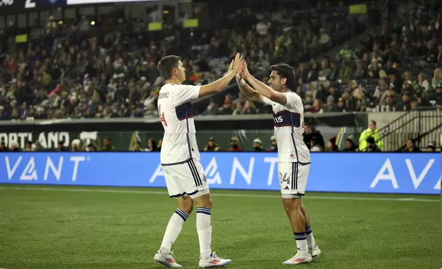 Vancouver Whitecaps Ranko Veselinović, left, Brian White, right, celebrate a goal against the Portland Timbers during the first half of an MLS soccer match Wednesday, Oct. 23, 2024, in Portland, Ore. (AP Photo/Howard Lao)