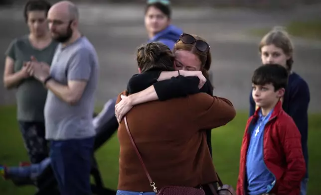 FILE - Lindsay Marlow, facing camera, hugs Courtney Majoros, in this Oct. 28, 2023 file photo, at a vigil in Lisbon Falls, Maine, for the victims of recent mass shootings. Majoros' brother, Maxx Hathaway, was one of the people killed in separate shootings in nearby Lewiston, Maine. (AP Photo/Robert F. Bukaty, File)