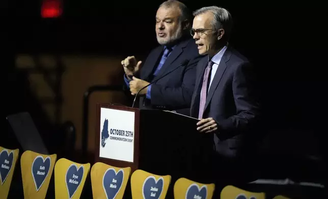 Tom Caron, right, master of ceremonies, speaks at a commemoration event to mark the one year anniversary of the mass shooting in Lewiston, Maine, Friday, Oct. 25, 2024. (AP Photo/Robert F. Bukaty)