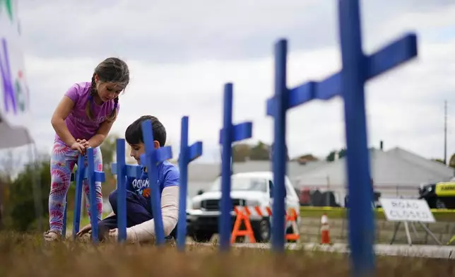 FILE - Lucy Allard, 5, and her brother Zeke Allard, 8, plant crosses in honor of the victims of this week's mass shooting in Lewiston, Maine, Oct. 28, 2023. (AP Photo/Matt Rourke)