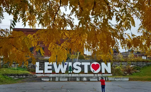 FILE - A man photographs a make-shift memorial at the base of the Lewiston sign at Veteran's Memorial Park, Oct. 29, 2023, in Lewiston, Maine. (AP Photo/Matt York, File)