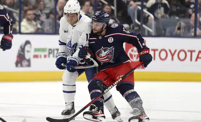 Columbus Blue Jackets forward Justin Danforth, right, checks Toronto Maple Leafs forward Max Domi during the first period of an NHL hockey game in Columbus, Ohio, Tuesday, Oct. 22, 2024. (AP Photo/Paul Vernon)