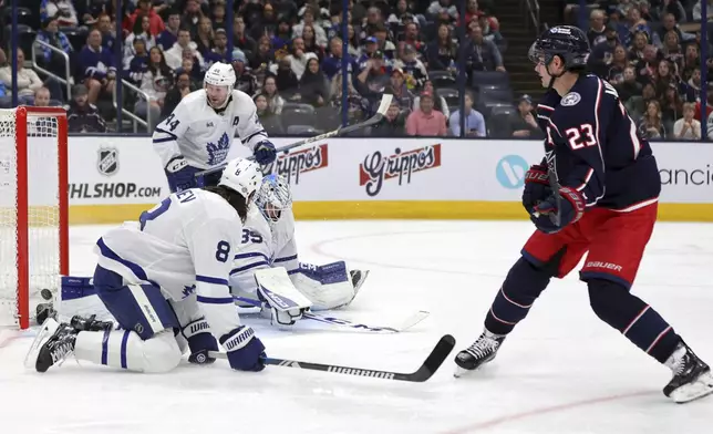 Columbus Blue Jackets defenseman Sean Monahan (23) scores past Toronto Maple Leafs goalie Dennis Hildeby, defenseman Christopher Tanev (8) and defenseman Morgan Rielly (44) during the second period of an NHL hockey game in Columbus, Ohio, Tuesday, Oct. 22, 2024. (AP Photo/Paul Vernon)