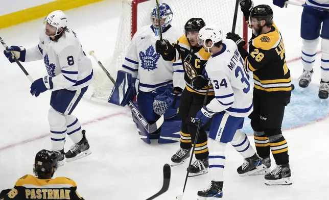 Boston Bruins' Brad Marchand (63) and Elias Lindholm (28) celebrate the goal by David Pastrnak (88) against Toronto Maple Leafs' Anthony Stolarz (41), Chris Tanev (8) and Auston Matthews (34) during the second period of an NHL hockey game, Saturday, Oct. 26, 2024, in Boston. (AP Photo/Michael Dwyer)
