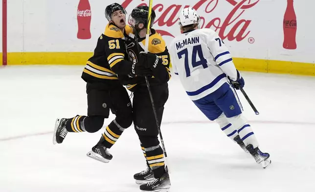 Boston Bruins' Justin Brazeau (55) celebrates his goal with Matthew Poitras (51) as Toronto Maple Leafs' Bobby McMann (74) skates away during the second period of an NHL hockey game, Saturday, Oct. 26, 2024, in Boston. (AP Photo/Michael Dwyer)