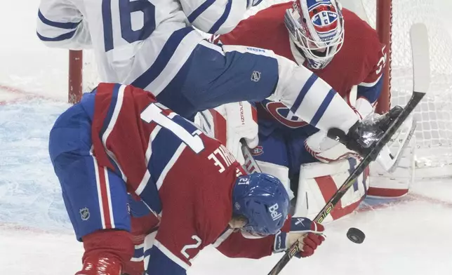 Montreal Canadiens goaltender Sam Montembeault (35) stops a shot by Toronto Maple Leafs' Mitch Marner (16) as Canadiens' Kaiden Guhle (21) defends during the first period of an NHL hockey game, Wednesday, Oct. 9, 2024 in Montreal. (Christinne Muschi/Canadian Press via AP)