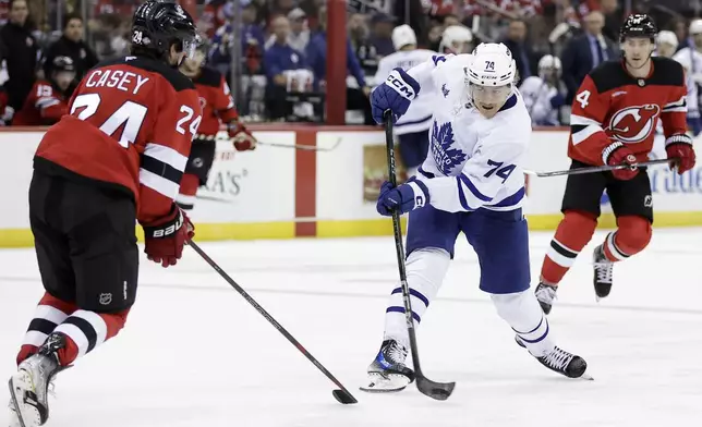 Toronto Maple Leafs center Bobby McMann (74) shoots in front of New Jersey Devils defenseman Seamus Casey (24) during the third period of an NHL hockey game Thursday, Oct. 10, 2024, in Newark, N.J. (AP Photo/Adam Hunger)