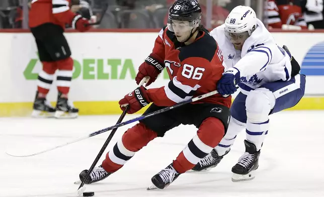 New Jersey Devils center Jack Hughes (86) controls the puck past Toronto Maple Leafs right wing William Nylander (88) during the third period of an NHL hockey game Thursday, Oct. 10, 2024, in Newark, N.J. (AP Photo/Adam Hunger)