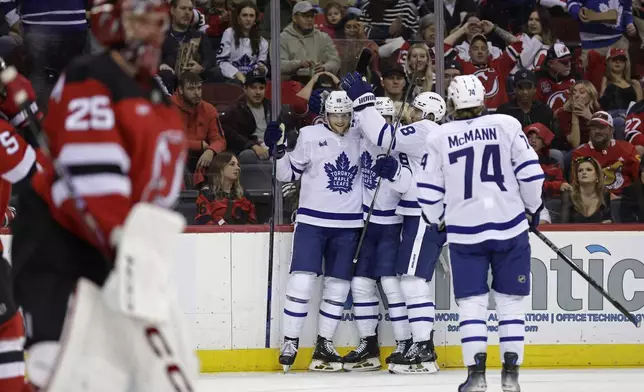 Toronto Maple Leafs center Steven Lorentz (18) is congratulated by teammates after scoring a goal past New Jersey Devils goaltender Jacob Markstrom (25) during the first period of an NHL hockey game Thursday, Oct. 10, 2024, in Newark, N.J. (AP Photo/Adam Hunger)