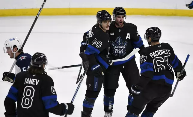 Toronto Maple Leafs' William Nylander (88) celebrates his goal with John Tavares (91), Max Pacioretty (67) and Christopher Tanev (8) against the Winnipeg Jets during the first period of an NHL hockey game in Winnipeg, Manitoba, Monday, Oct. 28, 2024. (Fred Greenslade/The Canadian Press via AP)