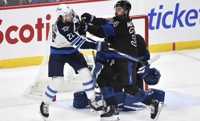 Toronto Maple Leafs' Austin Matthews (34) and Winnipeg Jets' Mason Appleton (22) battle for position in front of the net during the first period of an NHL hockey game in Winnipeg, Manitoba, Monday, Oct. 28, 2024. (Fred Greenslade/The Canadian Press via AP)