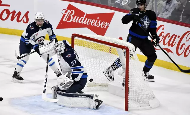 A shot from the Toronto Maple Leafs' William Nylander not pictured, scores on Winnipeg Jets' goaltender Connor Hellebuyck (37) during the first period of an NHL hockey game in Winnipeg, Manitoba, Monday, Oct. 28, 2024. (Fred Greenslade/The Canadian Press via AP)