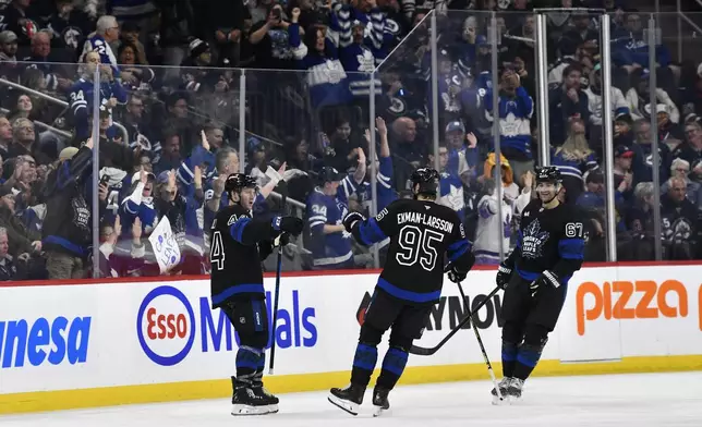 Toronto Maple Leafs' Morgan Rielly (44) celebrates after his goal against the Winnipeg Jets with Oliver Ekman-Larsson (95) and Max Pacioretty (67) during second-period NHL hockey game action in Winnipeg, Manitoba, Monday, Oct. 28, 2024. (Fred Greenslade/The Canadian Press via AP)