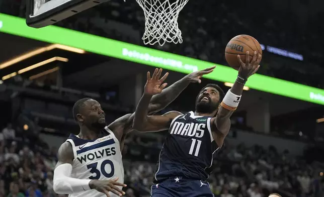 Dallas Mavericks guard Kyrie Irving (11) goes up for a shot as Minnesota Timberwolves forward Julius Randle (30) defends during the second half of an NBA basketball game, Tuesday, Oct. 29, 2024, in Minneapolis. (AP Photo/Abbie Parr)