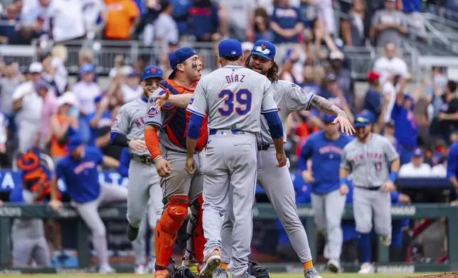 New York Mets pitcher Edwin Díaz, center, celebrates with teammates after winning the game in the ninth inning of a baseball game against the Atlanta Braves, Monday, Sept. 30, 2024, in Atlanta. (AP Photo/Jason Allen)