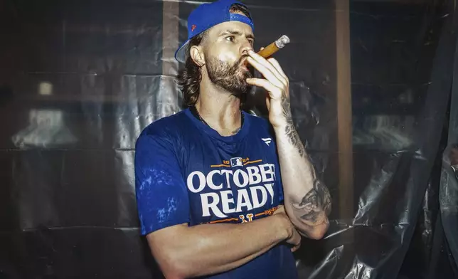 A New York Mets. player smokes a cigar in the locker room after clinching a playoff berth with a victory in the first baseball game of a doubleheader against the Atlanta Braves, Monday, Sept. 30, 2024, in Atlanta. (AP Photo/Jason Allen)