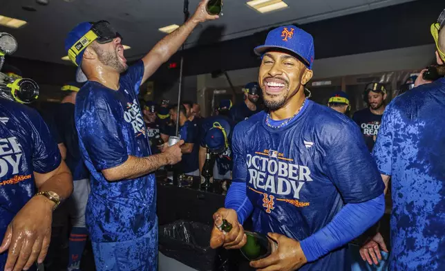 The New York Mets celebrate in the locker room after clinching a playoff berth with a victory in the first baseball game of a doubleheader against the Atlanta Braves, Monday, Sept. 30, 2024, in Atlanta. (AP Photo/Jason Allen)