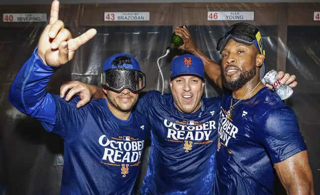 The New York Mets celebrate in the locker room after clinching a playoff berth with a victory in the first game of a doubleheader against the Atlanta Braves, Monday, Sept. 30, 2024, in Atlanta. (AP Photo/Jason Allen)