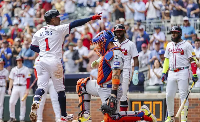 Atlanta Braves' Ozzie Albies, left, gestures to the crowd while stepping on home plate after hitting a two-run home run in the third inning of a baseball game against the New York Mets, Monday, Sept. 30, 2024, in Atlanta. (AP Photo/Jason Allen)