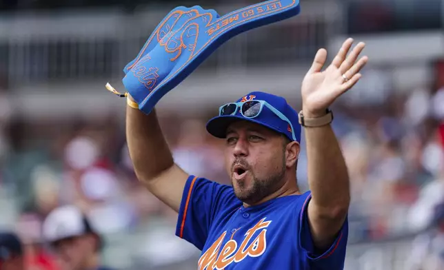 A fan dances in the stands during a rally in the eighth inning of a baseball game between the New York Mets and the Atlanta Braves, Monday, Sept. 30, 2024, in Atlanta. (AP Photo/Jason Allen)