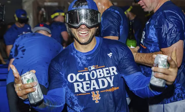 The New York Mets celebrate in the locker room after clinching a playoff berth with a victory in the first baseball game of a doubleheader against the Atlanta Braves, Monday, Sept. 30, 2024, in Atlanta. (AP Photo/Jason Allen)