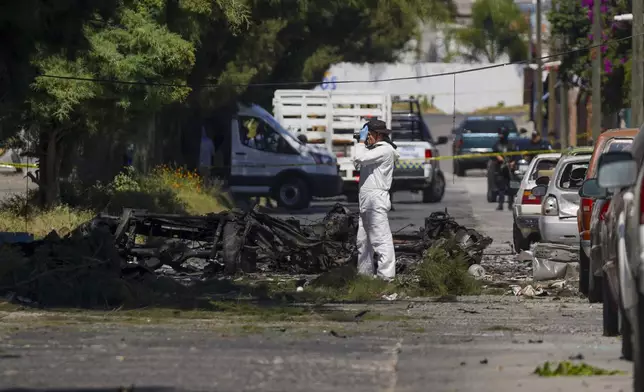 A forensic investigator works the scene where a car bomb exploded near a police station, in Acambaro, Guanajuato state, Mexico, Thursday, Oct. 24, 2024. (AP Photo/Armando Solis)