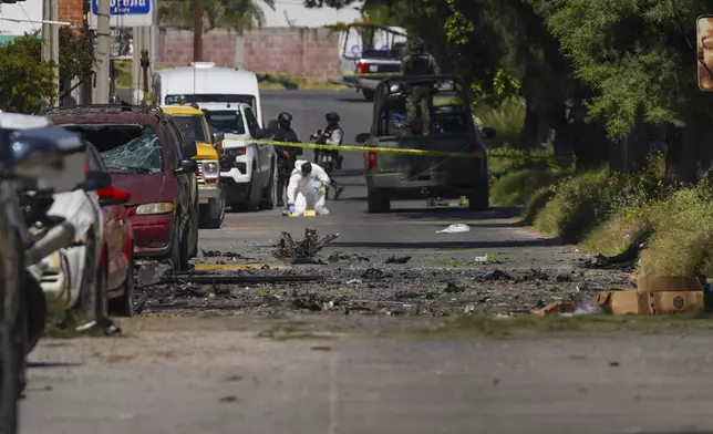 A forensic investigator works the scene where a car bomb exploded near a police station, in Acambaro, Guanajuato state, Mexico, Thursday, Oct. 24, 2024. (AP Photo/Armando Solis)