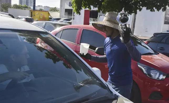 A musician collects tips from motorists in Culiacan, Sinaloa state, Mexico, Monday, Oct. 14, 2024. (AP Photo)