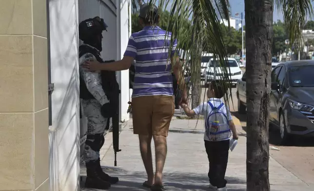 A resident pats a National Guard on the arm after picking a child up from school in Culiacan, Sinaloa state, Mexico, Monday, Oct. 14, 2024. (AP Photo)