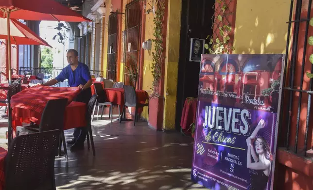 A waiter arranges a table outside the restaurant The Old Portales of Culiacan where a sign advertises two-for-one prices on drinks for women on Thursdays, in Culiacan, Sinaloa state, Mexico, Monday, Oct. 14, 2024. (AP Photo)