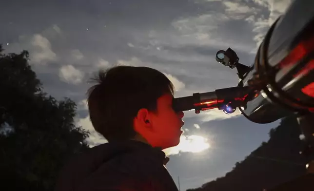 A youth looks through a telescope during a stargazing and comet-watching gathering at Joya-La Barreta Ecological Park in Queretaro, Mexico, Saturday, Oct. 19, 2024. (AP Photo/Ginnette Riquelme)