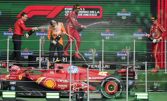 Ferrari driver Carlos Sainz of Spain, first place, center, Charles Leclerc of Monaco, third place, right, Riccardo Adami of Ferrari, left, and McLaren driver Lando Norris of Britain, second place, celebrate at the podium for the Formula One Mexico Grand Prix auto race at the Hermanos Rodriguez racetrack in Mexico City, Sunday, Oct. 27, 2024. (AP Photo/Eduardo Verdugo)