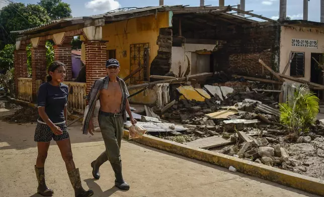 Residents walk past a house damaged by Hurricane John in Coyuca de Benitez, Guerrero state, Mexico, Monday, Sept. 30, 2024. (AP Photo/Felix Marquez)