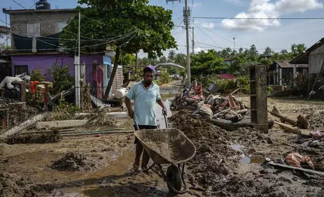 A man pushes a wheelbarrow through a damaged street after Hurricane John passed through Coyuca de Benitez, Guerrero state, Mexico, Monday, Sept. 30, 2024. (AP Photo/Felix Marquez)