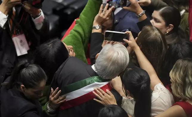 Outgoing President Andrés Manuel López Obrador poses for selfies as he arrives to Congress for the swearing-in ceremony of Claudia Sheinbaum as Mexico's new president in Mexico City, Tuesday, Oct. 1, 2024. (AP Photo/Fernando Llano)