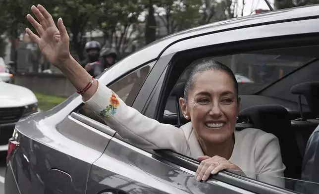 Claudia Sheinbaum waves from the vehicle taking her to Congress to be sworn in as president in Mexico City, Tuesday, Oct. 1, 2024. (AP Photo/Aurea Del Rosario)