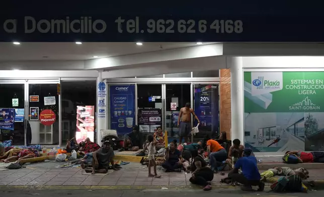 Migrants rest in front of a paint shop in Tapachula, Mexico, Sunday, Oct. 27, 2024. (AP Photo/Matias Delacroix)