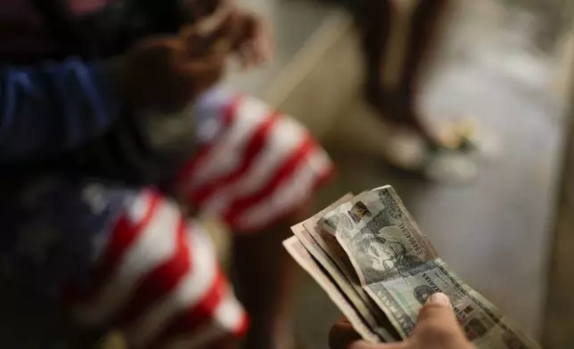 Honduran migrant Gerzon Zavala exchanges Guatemalan quetzales for Mexican pesos after crossing the Suchiate River, which marks the border between Guatemala and Mexico, from Ciudad Hidalgo, Mexico, Monday, Oct. 28, 2024. (AP Photo/Matias Delacroix)