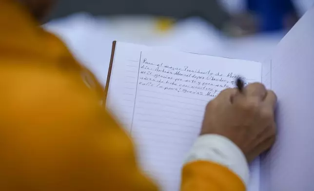 A supporter of Mexican President Andres Manuel Lopez Obrador writes him a letter as he gathers with other supporters outside the National Palace where he holds his last morning press conference, "La Mañanera," in Mexico City, Monday, Sept. 30, 2024. (AP Photo/Eduardo Verdugo)