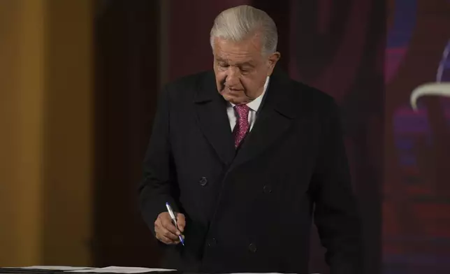 Mexican President Andres Manuel Lopez Obrador signs a law that puts the National Guard under the command of the military during his last morning press conference, "La Mañanera," at the National Palace in Mexico City, Monday, Sept. 30, 2024. (AP Photo/Fernando Llano)