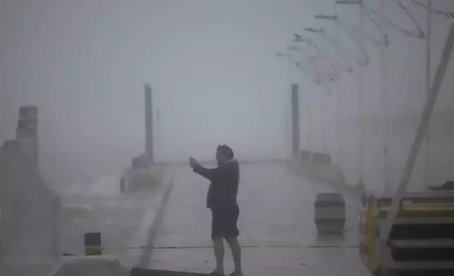 A person takes photos at the harbor amid rain as Hurricane Milton passes near Progreso, Yucatan state, Mexico, Tuesday, Oct. 8, 2024. (AP Photo/Martin Zetina)