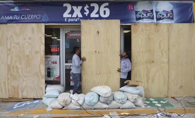 Workers board up a grocery store to protect it from Hurricane Milton, in Progreso, Yucatan state, Mexico, Monday, Oct. 7, 2024. (AP Photo/Martin Zetina)