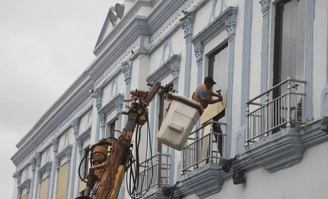 A man boards up a government building to protect it from Hurricane Milton, in Progreso, Yucatan state, Mexico, Monday, Oct. 7, 2024. (AP Photo/Martin Zetina)