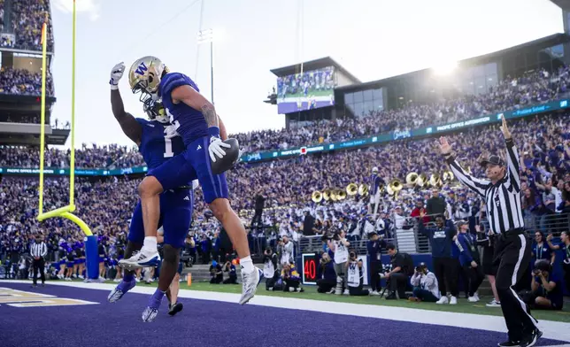 Washington wide receiver Denzel Boston, front, celebrates his touchdown with running back Jonah Coleman (1) during the first half of an NCAA college football game against Michigan, Saturday, Oct. 5, 2024, in Seattle. (AP Photo/Lindsey Wasson)